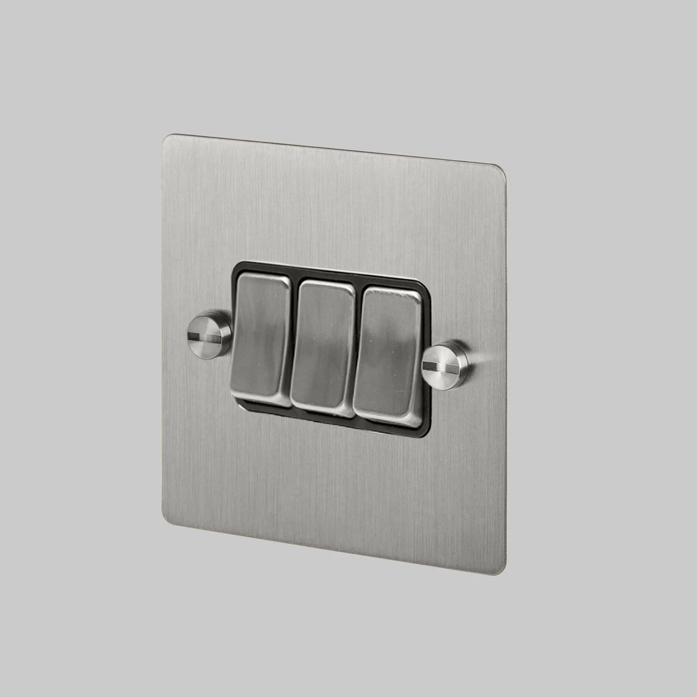 Metallic light switch panel with three silver buttons on a gray background