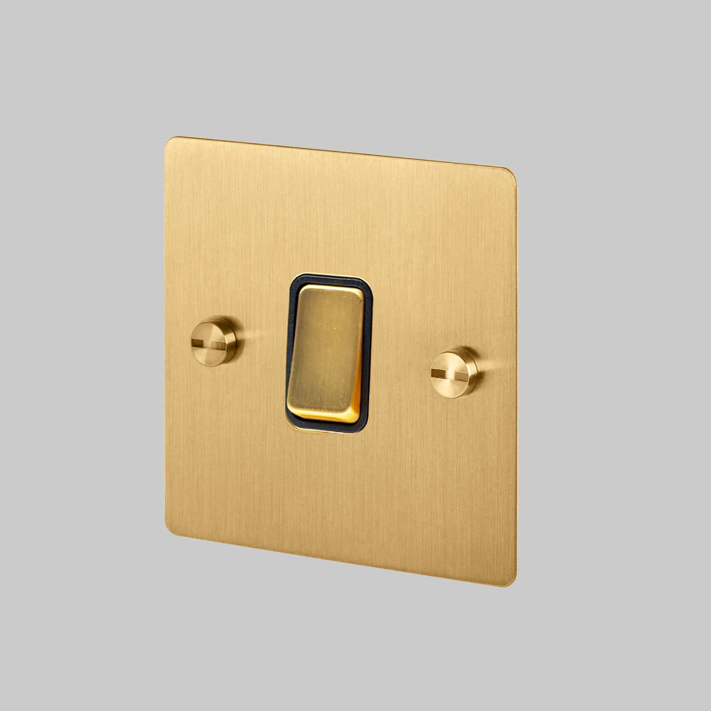 brass light switch with a black insert on a gray background